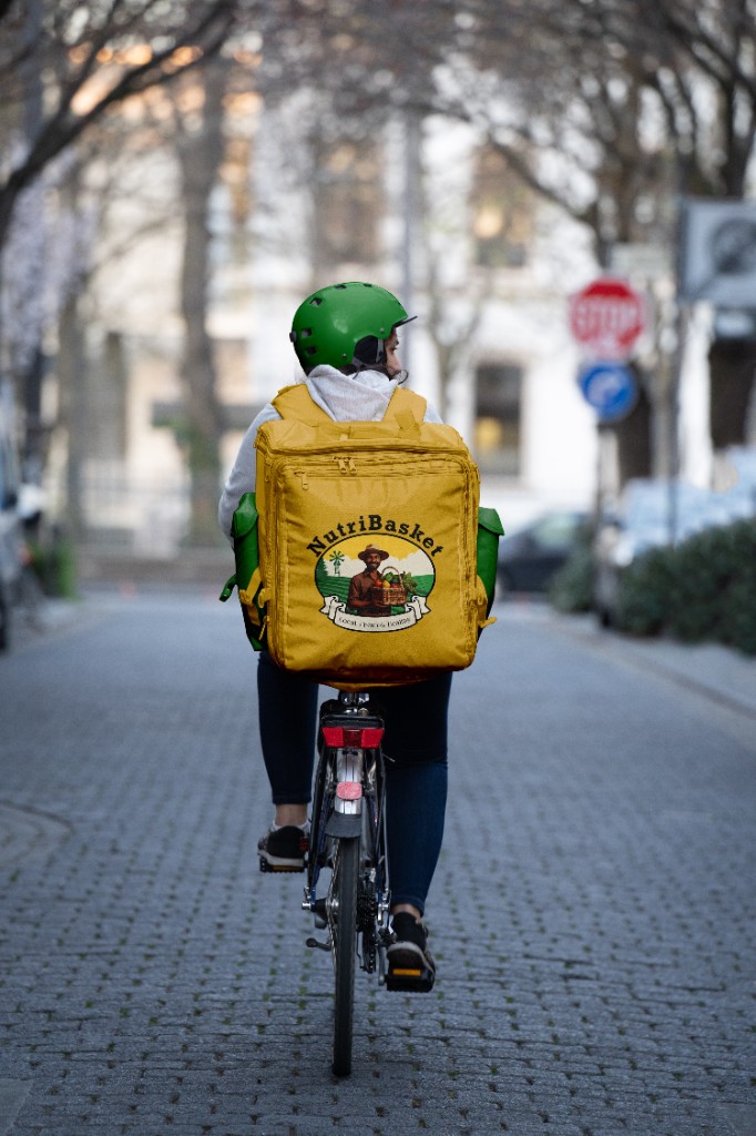 NutriBasket delivery rider with branded backpack on city street